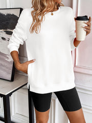 White relaxed fit sweatshirt with crew neck and pockets, styled with black shorts.