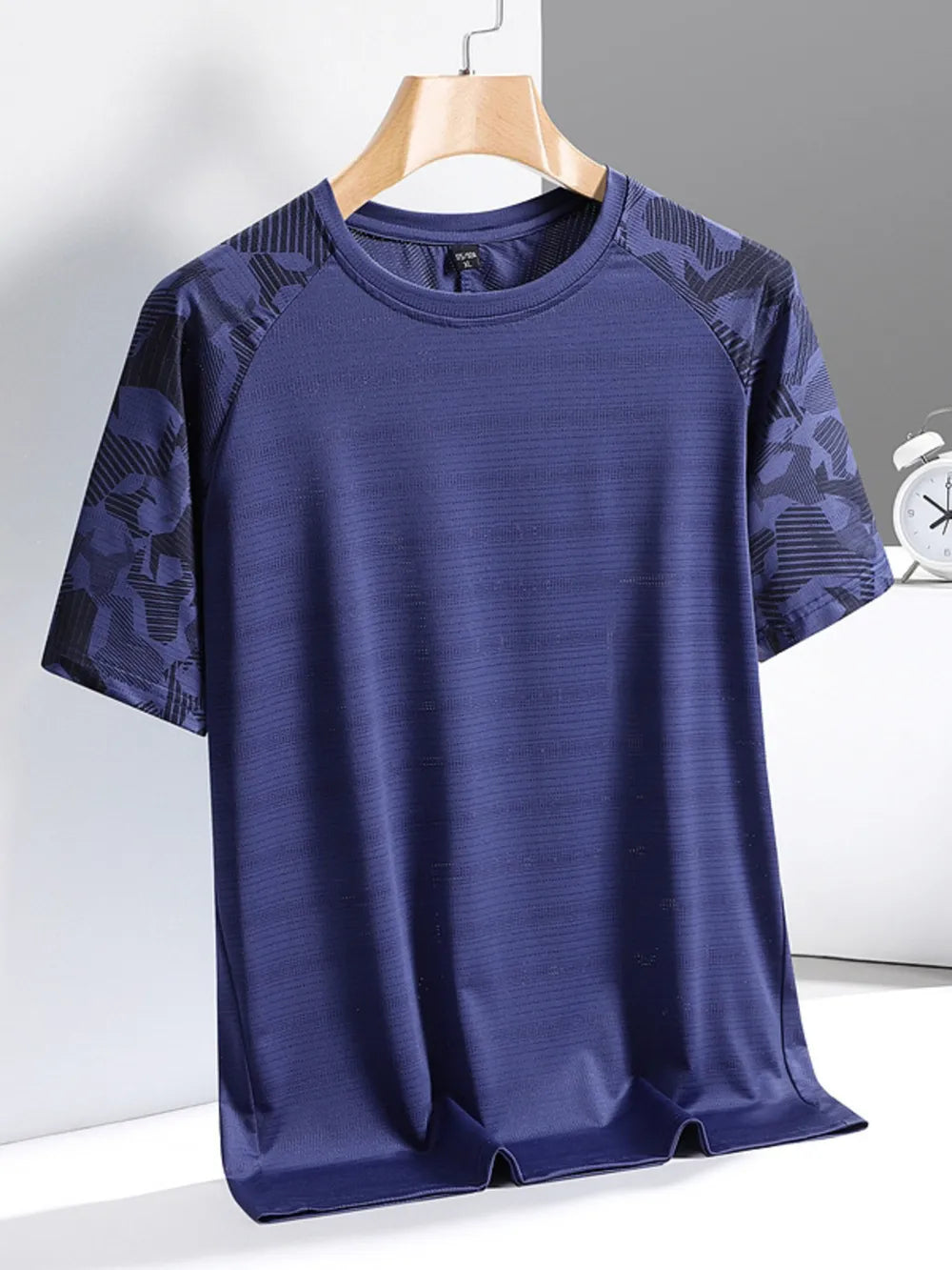 Men's blue activewear tee with patterned raglan sleeves and textured fabric.