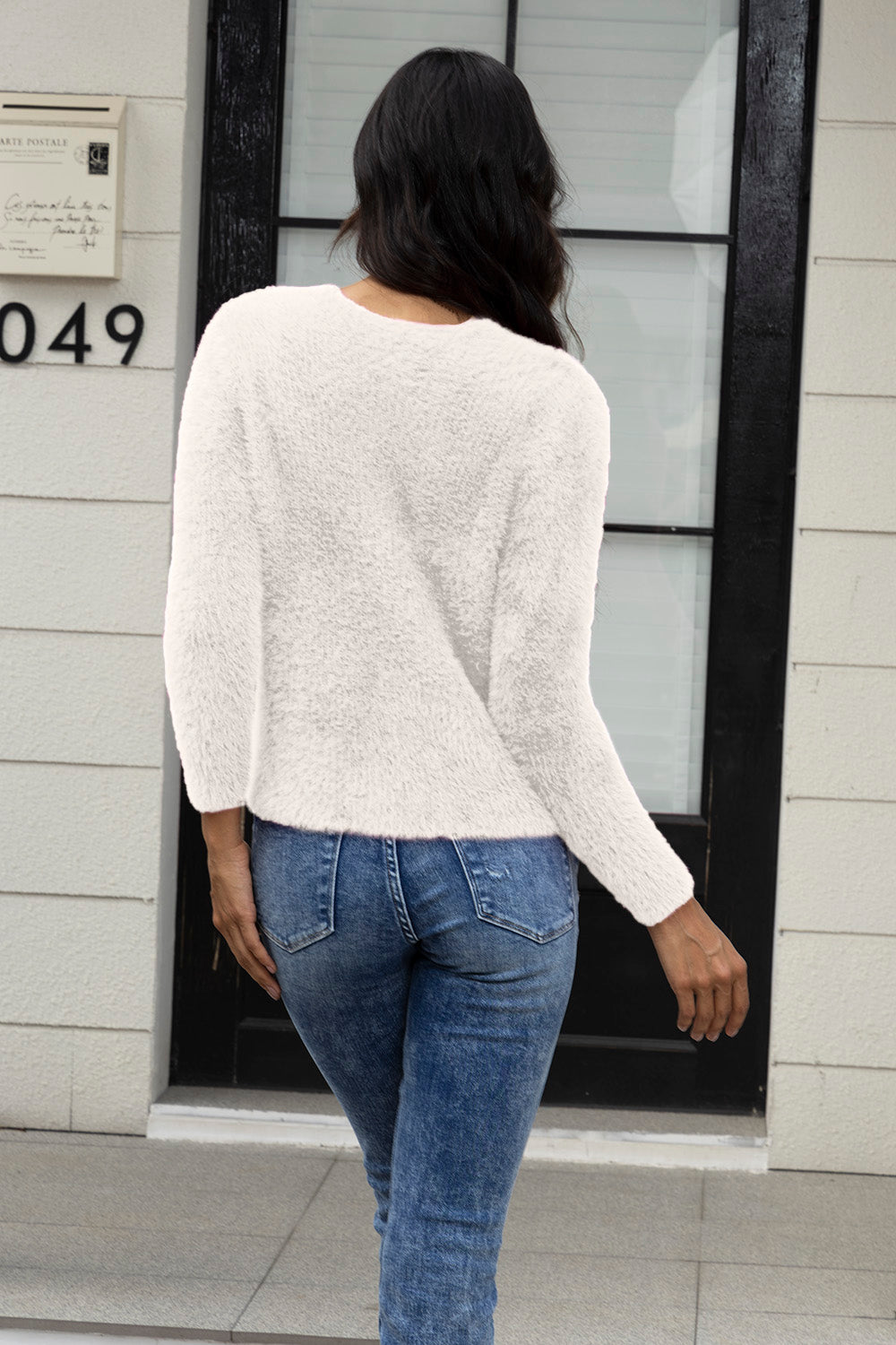 Ivory fluffy knit cardigan with long sleeves, styled with blue jeans.