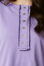 Lavender sweatshirt with button henley neckline and raw edge detail.