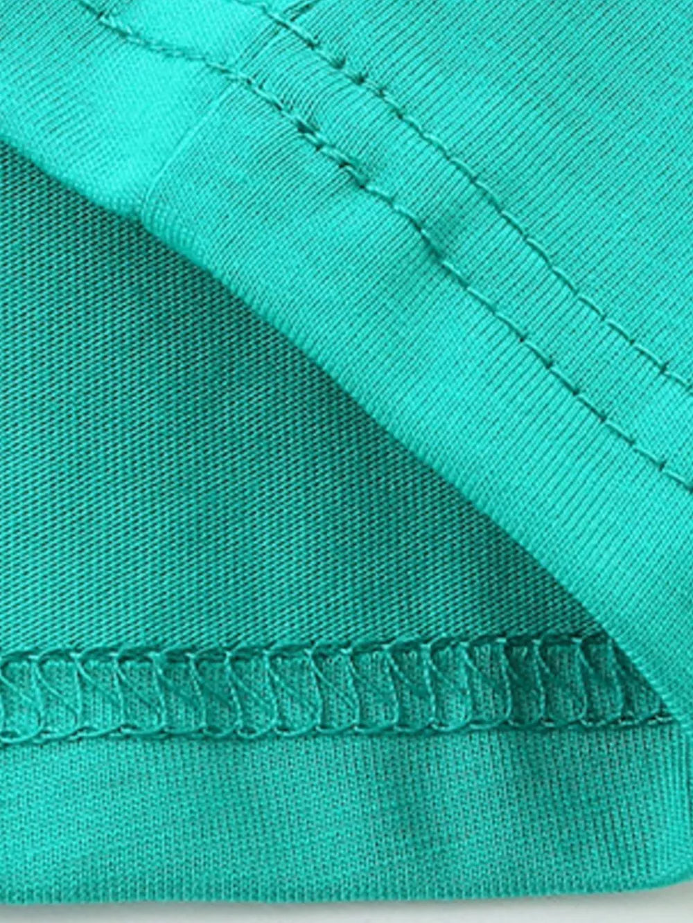 Teal cotton t-shirt detail showing crew neck stitching and hem.