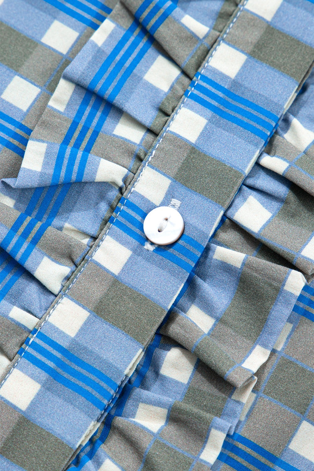 Blue plaid button-down blouse with frilled detail and white button.