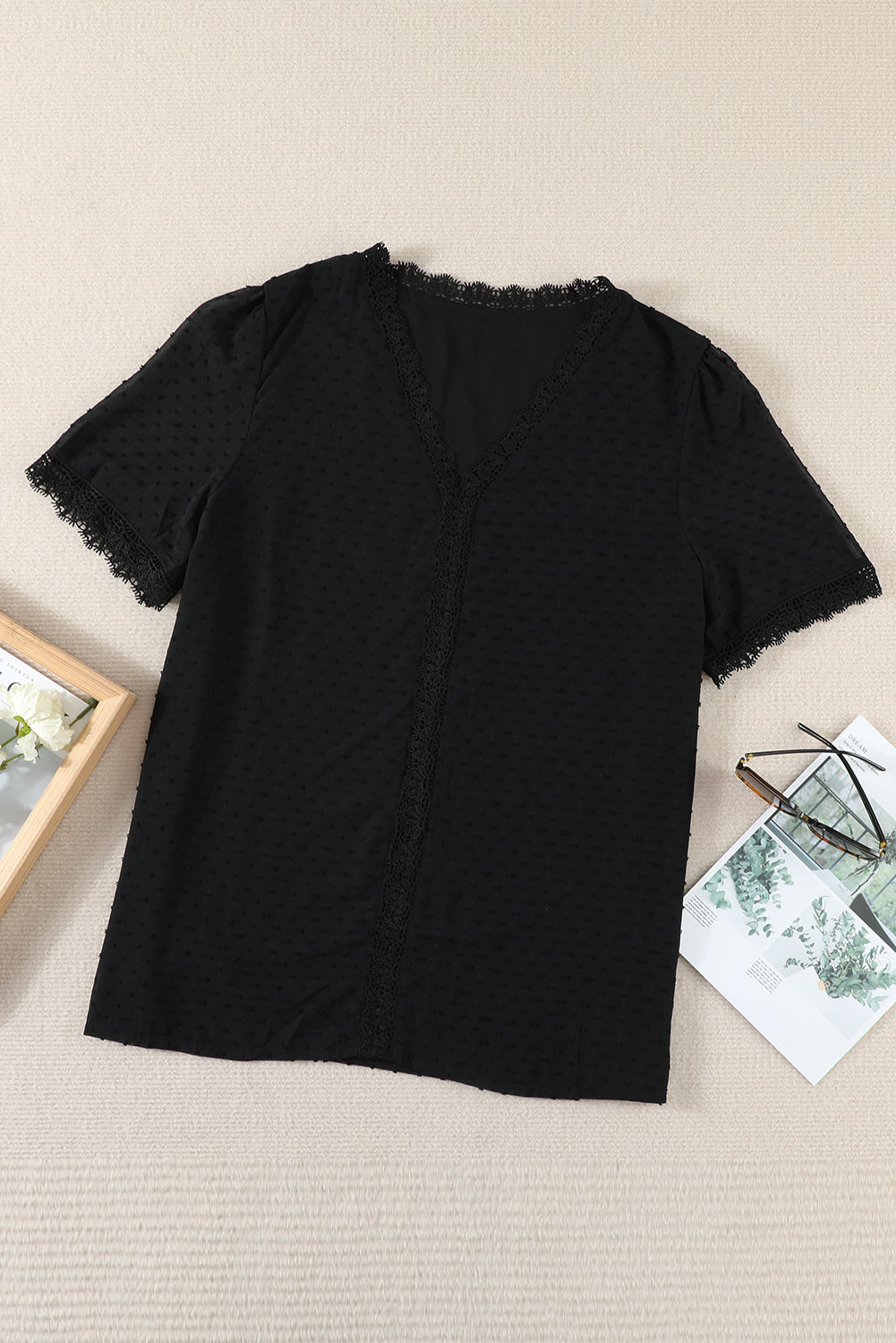 Black textured dot blouse with lace trim V-neck and short sleeves.