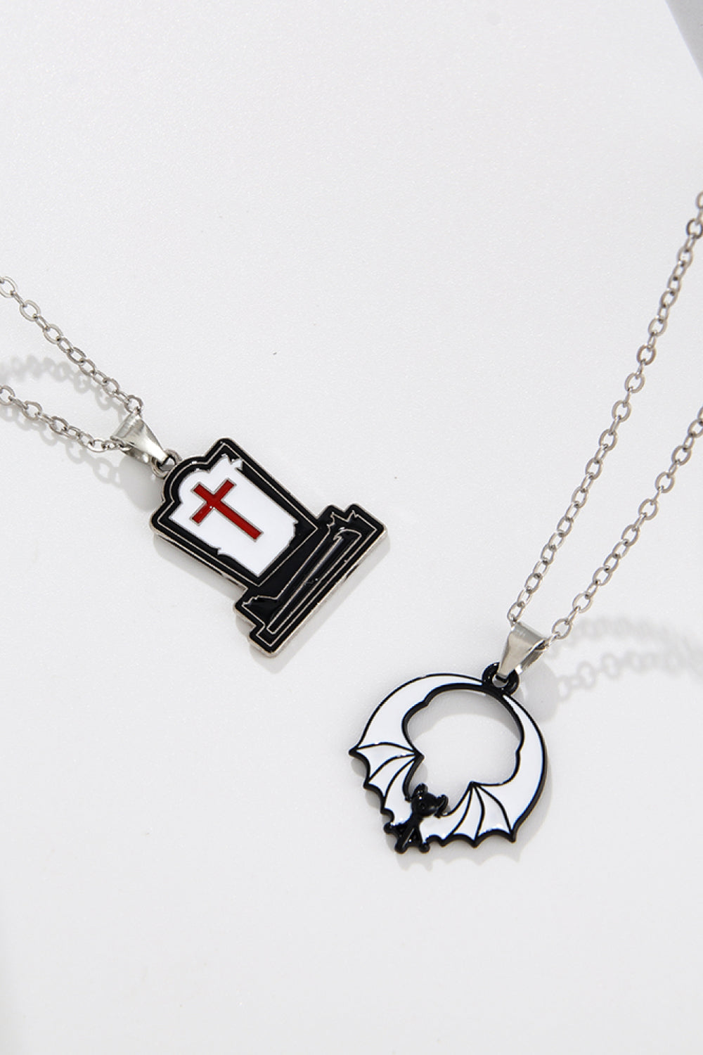 Spooky Season enamel pendant necklaces, one tombstone with red cross, one bat in circle.