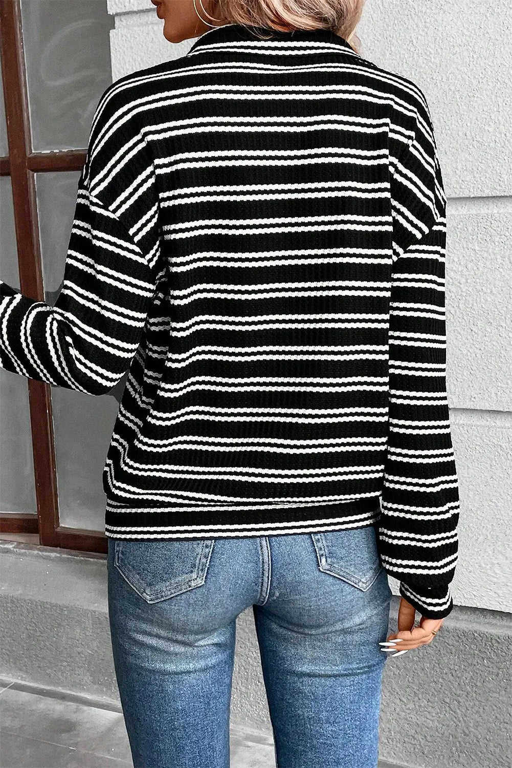 Black and white striped ribbed half-zip pullover sweater with long sleeves.