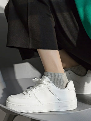 White minimalist platform sneakers with lace-up closure and ribbed sole.