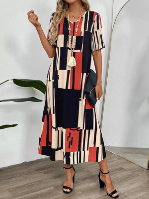 Geometric V-neck midi dress in dark blue, red, and cream with short sleeves and a flowing skirt.