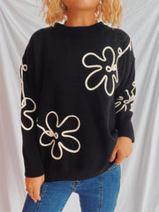 Black knit sweater with white floral outline pattern, crew neck, long sleeves.