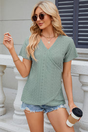 Light green eyelet wrap V-neck top with short sleeves and a textured pattern.