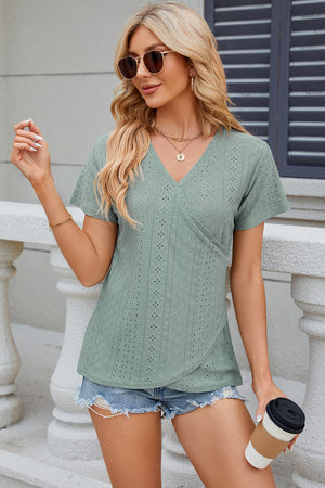 Light green eyelet wrap V-neck top with short sleeves and a textured pattern.