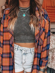 Oversized plaid shacket in orange, blue, and purple with a relaxed fit, worn open over a striped crop top.