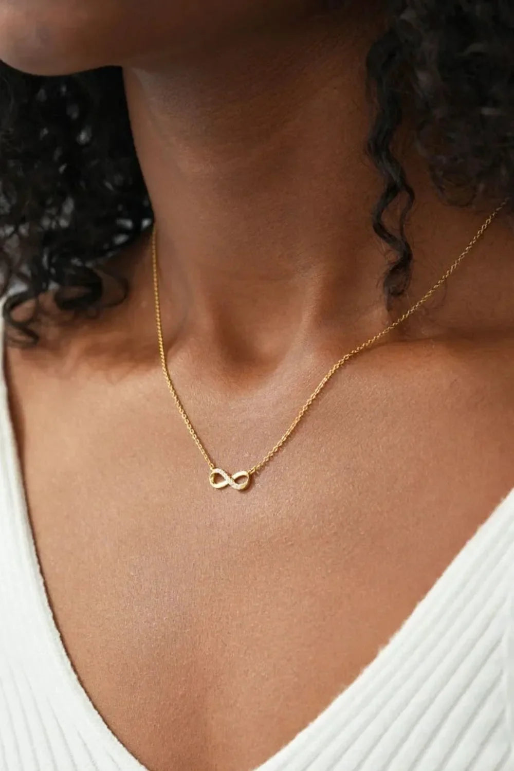 Gold infinity symbol pendant necklace on a delicate chain.