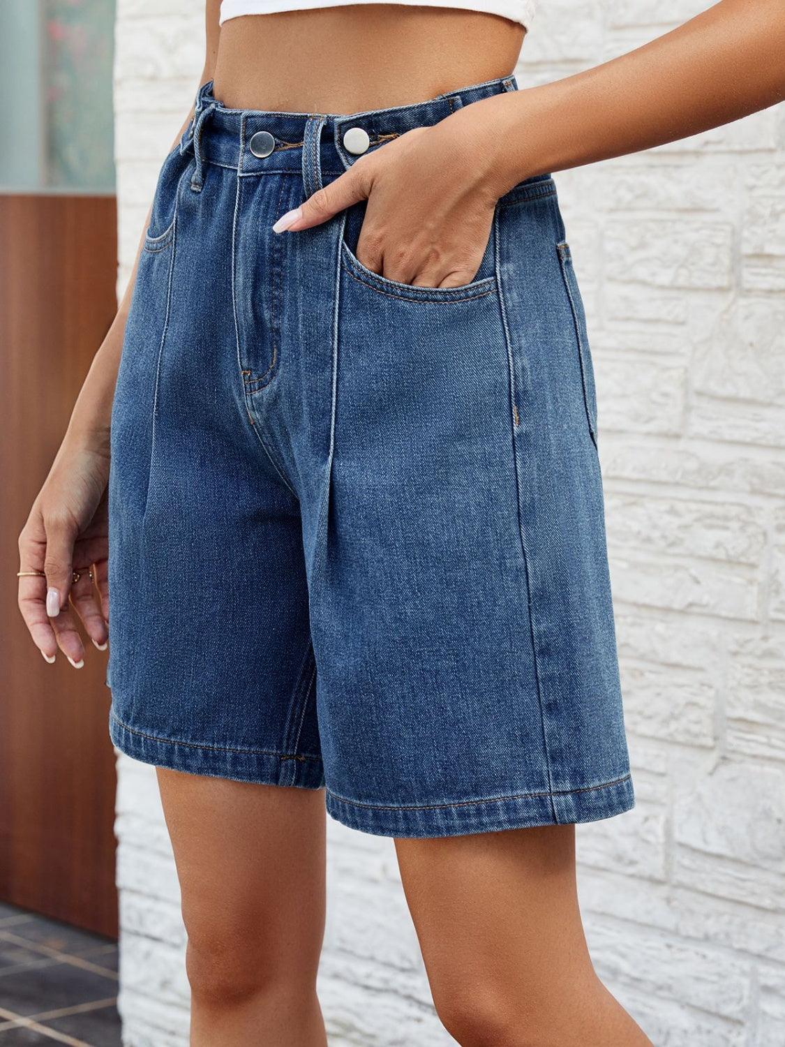 Pleated denim bermuda shorts in medium wash with button closure and front pockets.