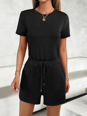 Black t-shirt romper with short sleeves, crew neck, drawstring waist, and side pockets.