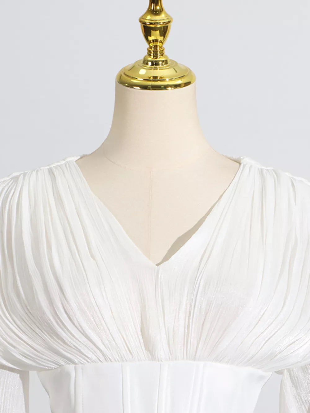 White mini dress with V-neck, ruched bodice, and balloon sleeves.