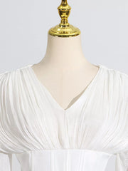 White mini dress with V-neck, ruched bodice, and balloon sleeves.