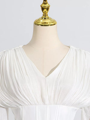 White mini dress with V-neck, ruched bodice, and balloon sleeves.