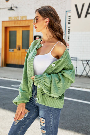 Green textured bubble sleeve cropped cardigan with button front and open knit details.