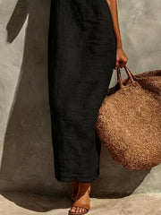 Black linen-blend maxi dress with a relaxed fit, styled with a straw tote bag.