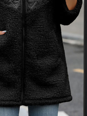 Black teddy hoodie with quilted panel detail and zip closure.
