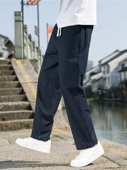 Navy blue men's sweatpants with white drawstring and pockets, worn with white sneakers.