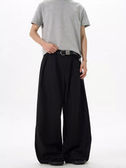 Black relaxed fit sweatpants with pleats and a wide leg, styled with a belt.