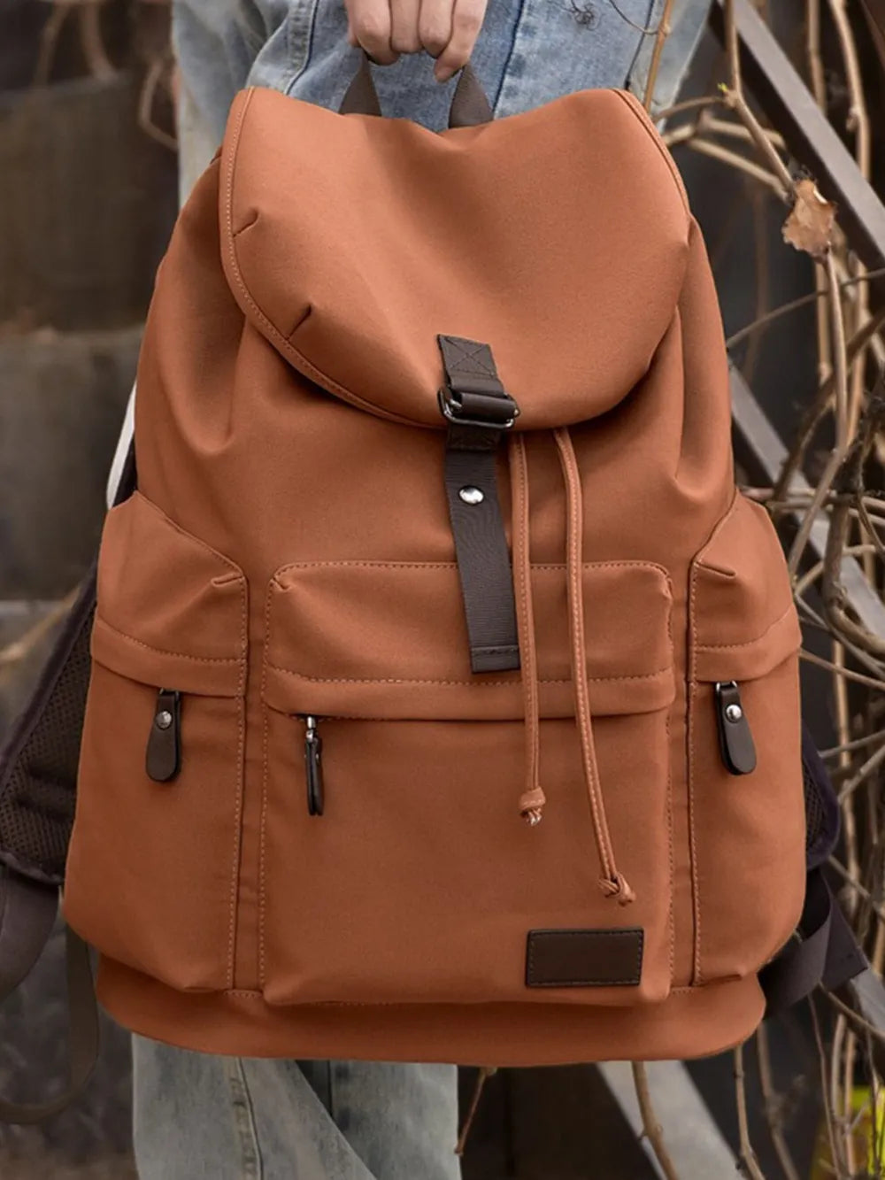 Ochre canvas backpack with brown leather accents and multiple pockets.