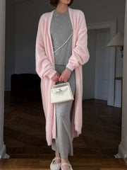 Plush pink maxi cardigan with balloon sleeves worn open over a gray dress.