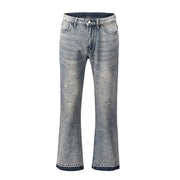 Distressed wash bootcut jeans with raw hem in medium blue denim, featuring paint splatters and fading.