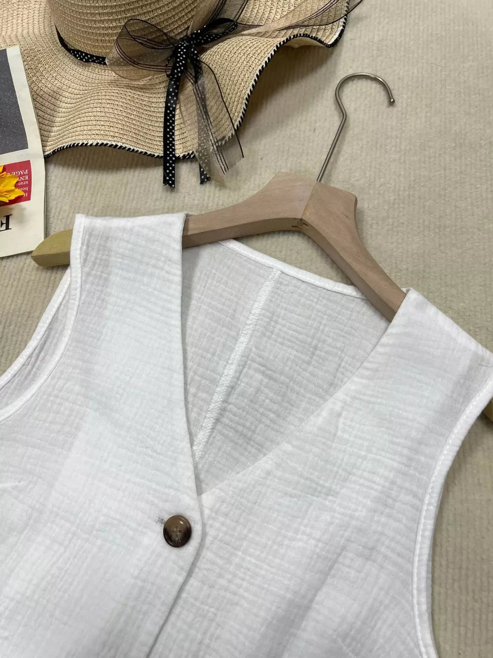 White textured vest with tortoiseshell button and V-neck