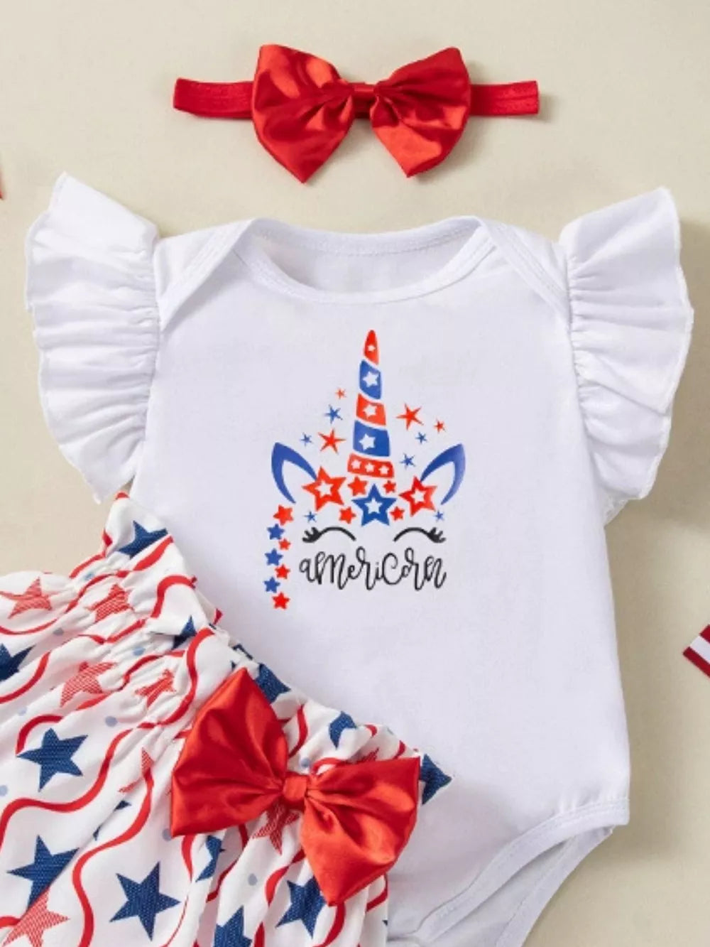 Baby unicorn outfit with patriotic stars and stripes, includes ruffled sleeves, bloomer shorts and red bow headband.