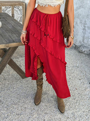 Scarlet midi skirt with cascading ruffles and a thigh-high slit, styled with boots.