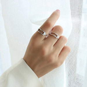 Sculptural silver rings with pearl accents, featuring an open oval design.