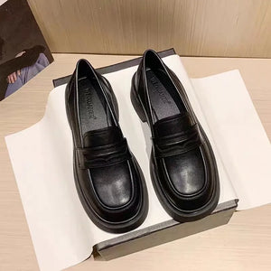 Black leather platform penny loafers with a chunky sole and classic strap detail.
