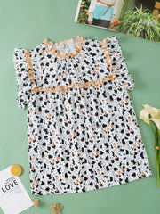 White blouse with terrazzo print, ruffle yoke, and short sleeves.