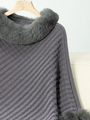 Dark gray knit poncho with faux fur trim at the collar and cuffs.