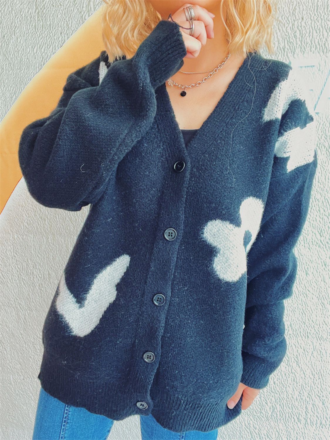 Black acrylic cardigan with playful white floral and chevron appliques, V-neck, button front.