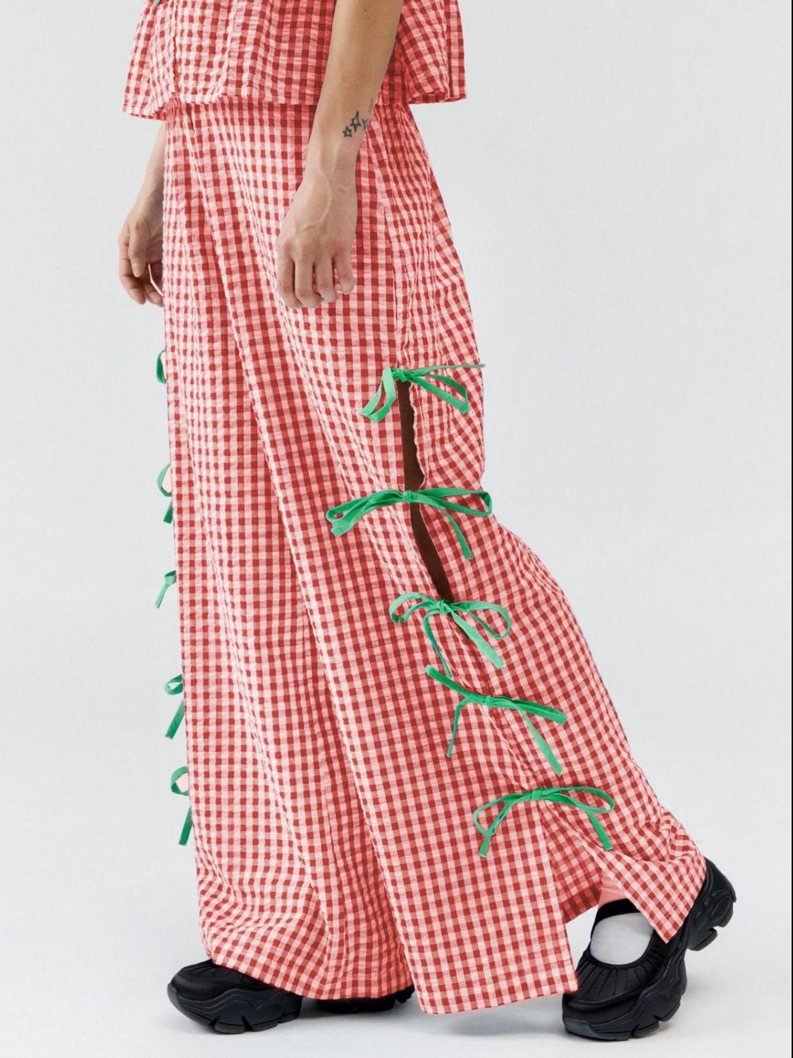 Red gingham wide-leg trousers with green bow details on the side slits.
