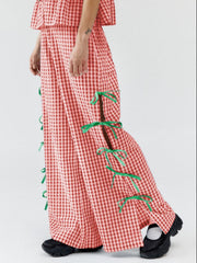 Red gingham wide-leg trousers with green bow details on the side slits.