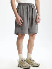 Men's gray chino shorts with drawstring and pockets, styled with crew socks and sneakers.