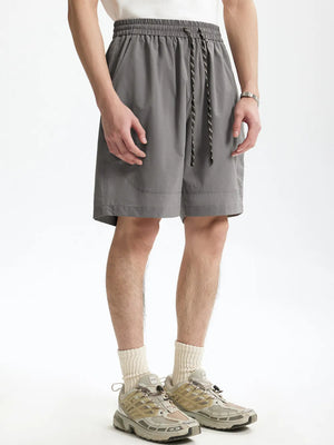 Men's gray chino shorts with drawstring and pockets, styled with crew socks and sneakers.