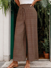 Brown textured smocked waist wide-leg trousers with a drawstring detail.