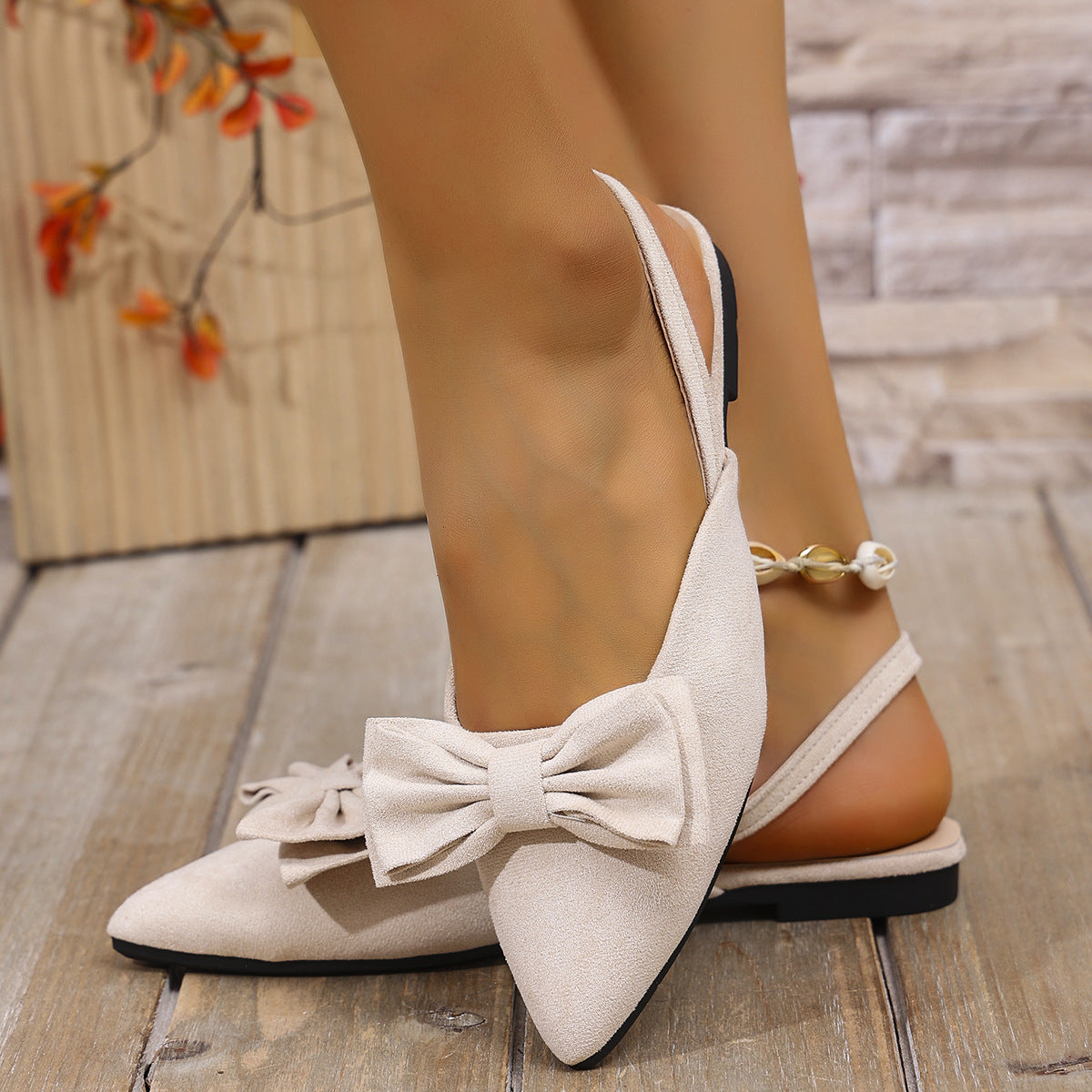 Beige bow accent slingback slip-on flats with pointed toe and ankle strap.