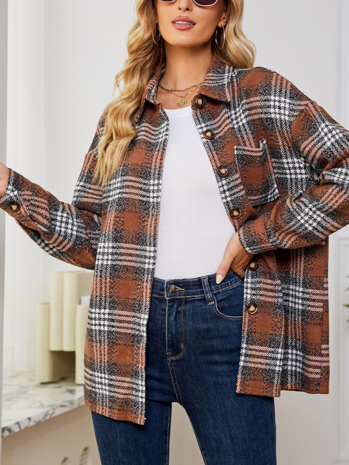Brown plaid shacket with oversized button detail and chest pocket, worn open over a white top.