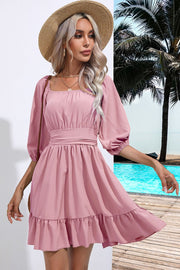 Blush pink mini dress with square neckline, puff sleeves, and ruffled hem.