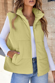 Padded corduroy vest in sage with a high collar and zip front, styled with jeans.