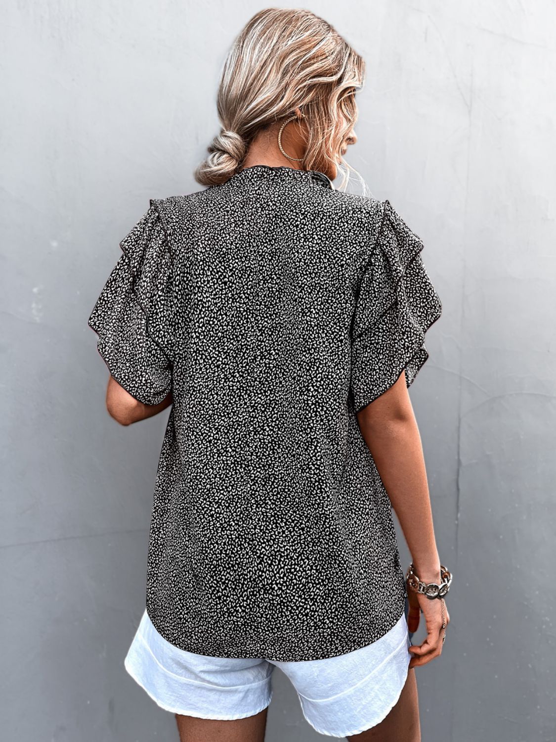 Black ditsy print blouse with ruffle sleeves and a high neckline.