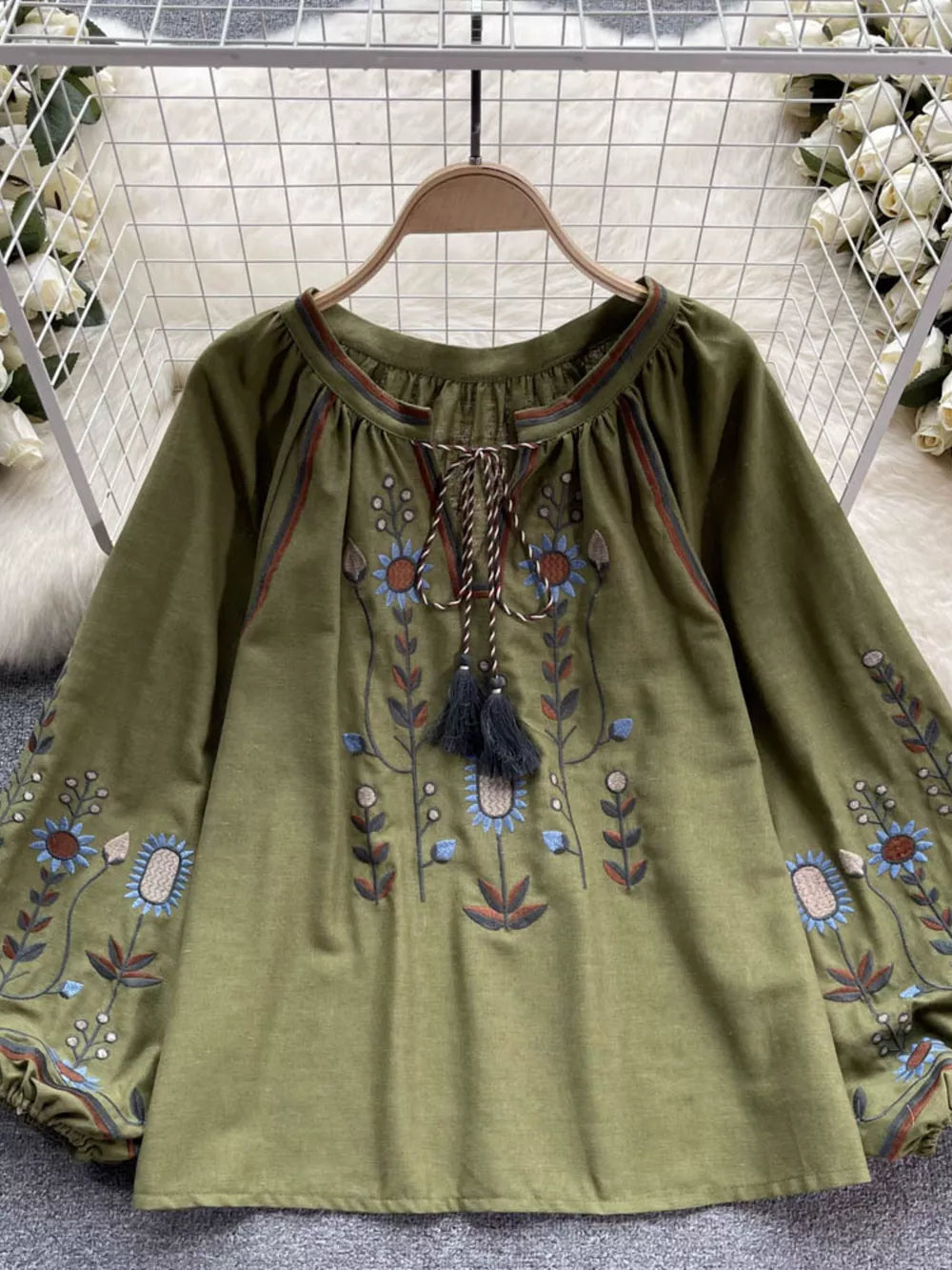 Green embroidered tie neck blouse with billowy sleeves and floral details.