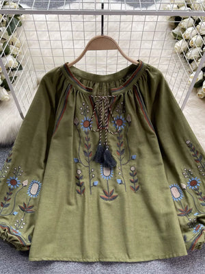 Green embroidered tie neck blouse with billowy sleeves and floral details.