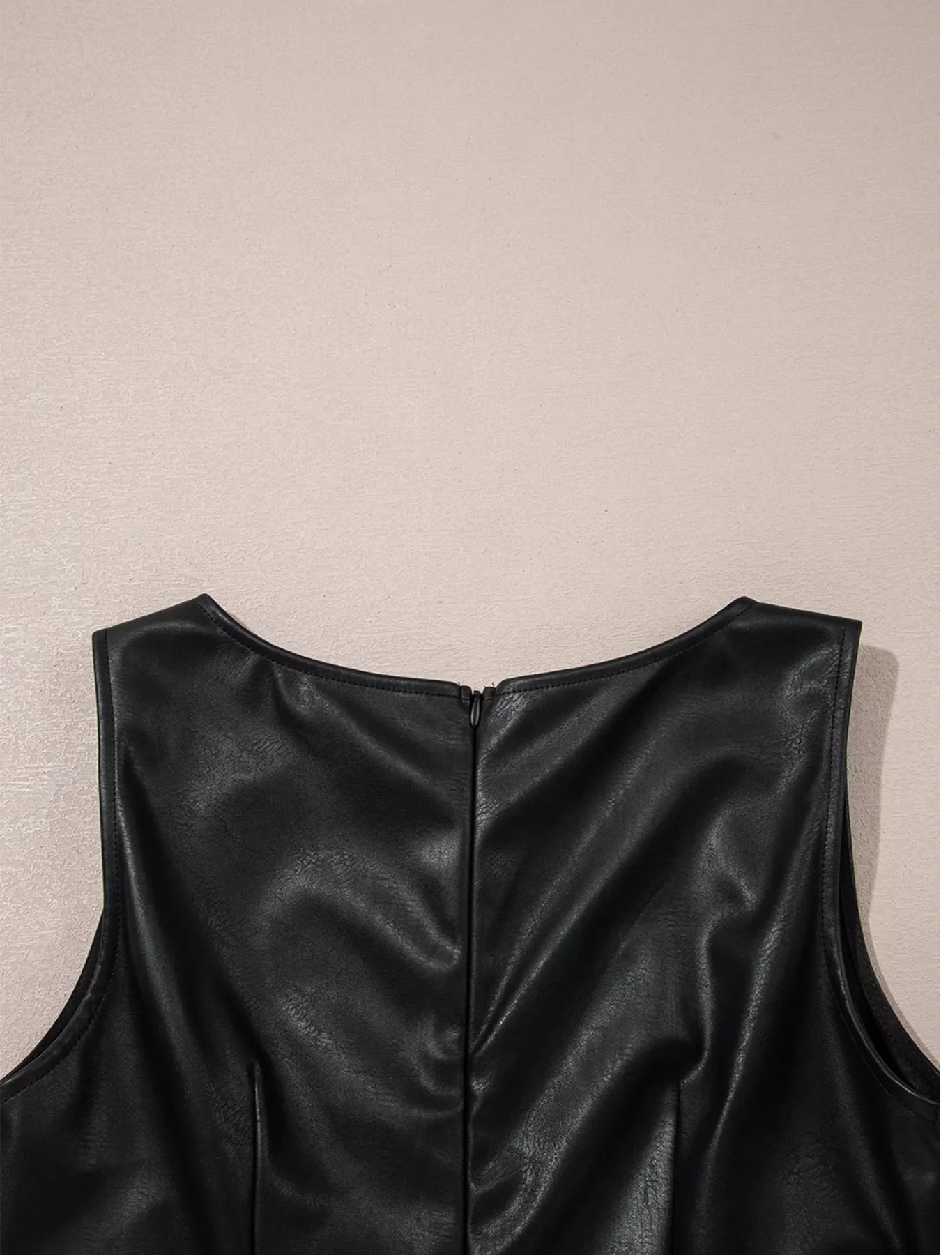 Black vegan leather sleeveless mini dress with a back zipper detail.